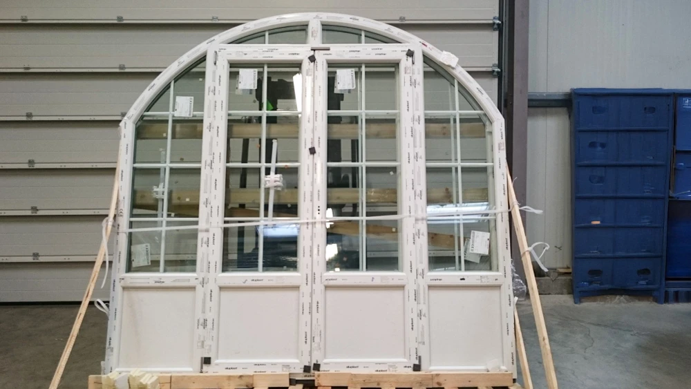 Atelier industriel intérieur avec porte-fenêtre cintrée en PVC blanc en cours d'assemblage