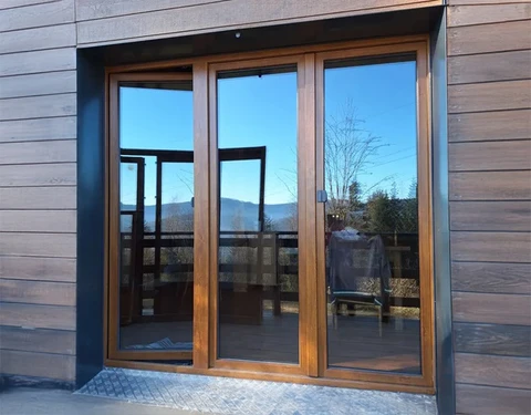 Façade extérieure d'habitation contemporaine avec grande baie vitrée coulissante trois vantaux en bois
